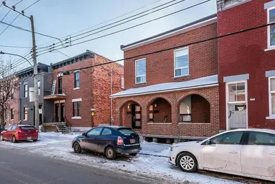 two cars parked on a snowy street in front of buildings at Cohabs Montréal in Montréal