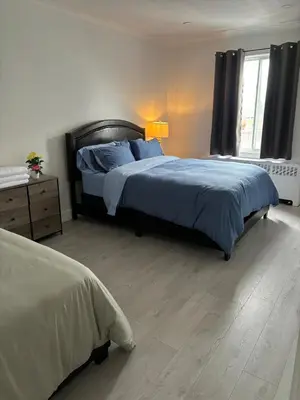 a bedroom with two beds with blue sheets and a window at Shop & Stay Central 8 in Montréal