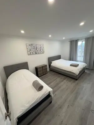 two beds in a room with white walls and wooden floors at Shop & Stay Central 6 in Montréal