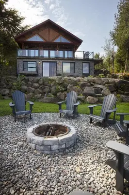 two chairs and a fire pit in front of a house at Log cabin - Lakeside - Le Oly in Saint Romain
