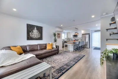 a living room with a brown leather couch and a kitchen at Great Gaston in Longueuil