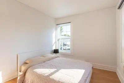 a white bedroom with a bed and a window at Chez Flo in Trois-Rivières