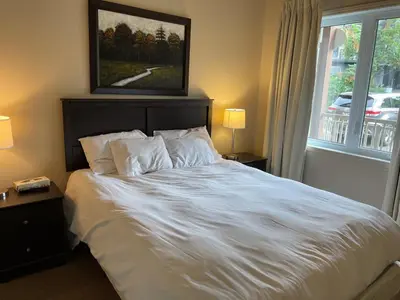 a bedroom with a large white bed with a window at Superbe ski-in ski-out condo in Bromont