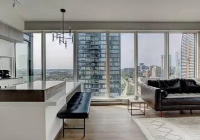 a living room with a couch and a kitchen with large windows at TDC2 - 28th floor - 2 bd, 2 bth in Montréal