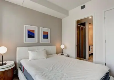 a white bedroom with a white bed and two lamps at TDC2 - 28th floor - 2 bd, 2 bth in Montréal