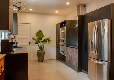 a kitchen with a stainless steel refrigerator and black cabinets at Modern Apartment - Home Theater and Premium Kitchen in Terrebonne