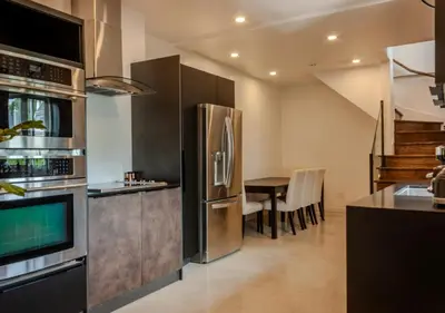 a kitchen with a stainless steel refrigerator and a table at Modern Apartment - Home Theater and Premium Kitchen in Terrebonne