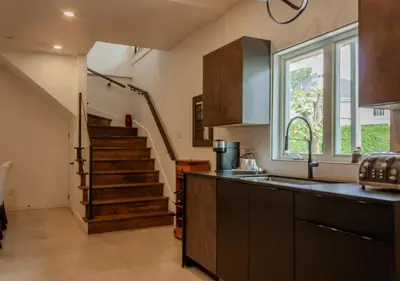 a kitchen with a sink and a staircase in the background at Modern Apartment - Home Theater and Premium Kitchen in Terrebonne