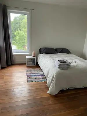 a white bedroom with a bed and a window at House on a beautiful maple grove in Valcourt