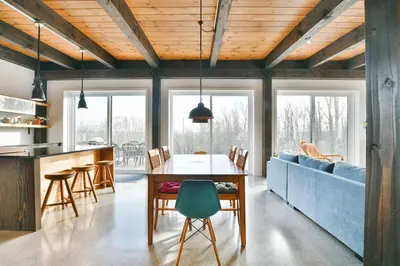 a kitchen and dining room with a table and a blue couch at House on a beautiful maple grove in Valcourt