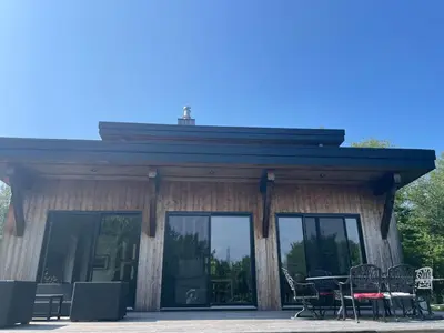 a building with glass doors and tables and chairs at House on a beautiful maple grove in Valcourt