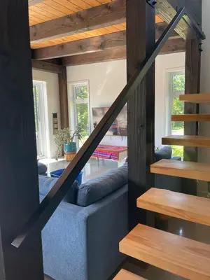 a staircase leading up to a living room with wooden ceilings at House on a beautiful maple grove in Valcourt
