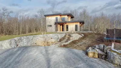 a house on a hill with a stone wall at House on a beautiful maple grove in Valcourt