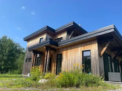 a wooden house with a gambrel roof at House on a beautiful maple grove in Valcourt