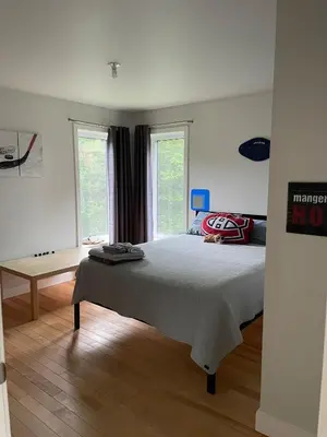 a bedroom with a bed and two windows at House on a beautiful maple grove in Valcourt