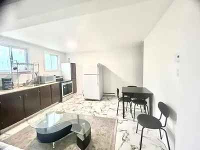 a kitchen with a table and chairs and a refrigerator at Downtown 2B Basement Unit in Montréal