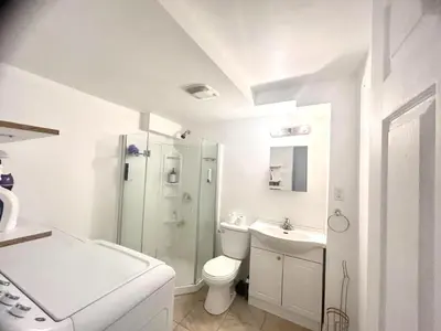 a white bathroom with a toilet and a sink at Downtown 2B Basement Unit in Montréal
