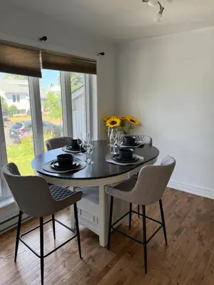 a dining room with a table with chairs and flowers at Chambre queen near Montreal in Sainte-Catherine