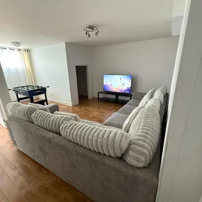 a living room with a couch and a flat screen tv at Chambre queen near Montreal in Sainte-Catherine