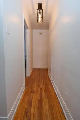 an empty hallway with white walls and wood floors at Van Horne Black VIP in Montréal