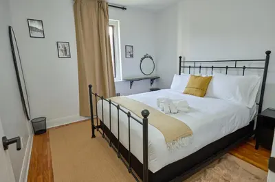 a bedroom with a bed with white sheets and gold pillows at Van Horne Black VIP in Montréal