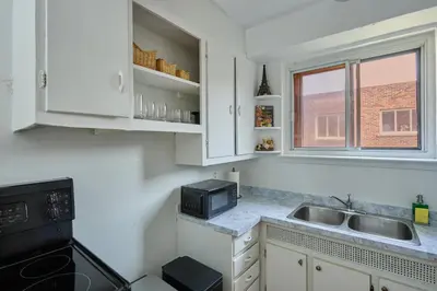 a kitchen with white cabinets and a sink and a microwave at Van Horne Black VIP in Montréal