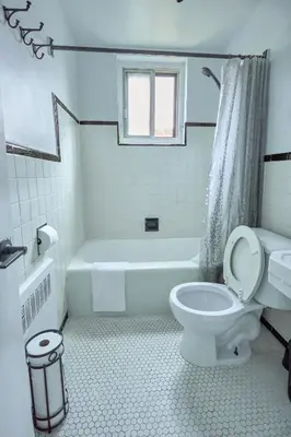 a white bathroom with a toilet and a bath tub at Van Horne Black VIP in Montréal