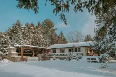 a house with snow on the ground in front of it at Spa Scandinave - Les Balancoires in Mansonville