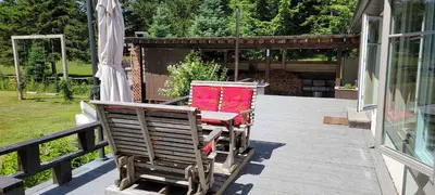 two chairs sitting on a deck next to a house at Spa Scandinave - Les Balancoires in Mansonville
