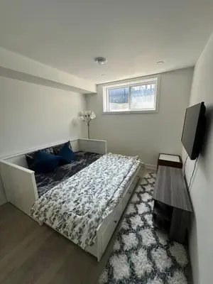 a bedroom with a large bed and a television at Baraqah Residence Gorgeous New 5BD Home 15mins-MTL in Longueuil