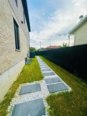 a garden with stepping stones next to a building at Baraqah Residence Gorgeous New 5BD Home 15mins-MTL in Longueuil