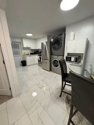 a kitchen with a washer and dryer and a table and chair at Private Basement Suite in Laval in Laval