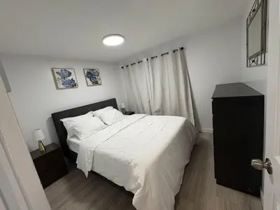 a bedroom with a bed with white sheets and a window at Private Basement Suite in Laval in Laval