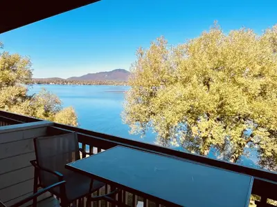 a table on a balcony with a view of a lake at Lumineux condo au bord du lac in Magog-Orford