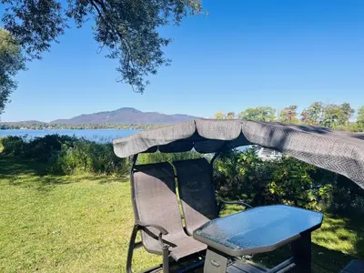 a chair under a tent with a view of a lake at Lumineux condo au bord du lac in Magog-Orford