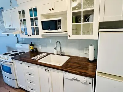 a kitchen with white cabinets and a sink and a refrigerator at Lumineux condo au bord du lac in Magog-Orford