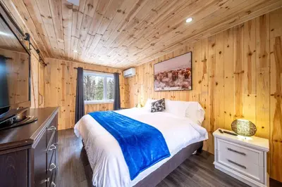 a bedroom with a bed in a wooden wall at Nature Spa & Lake Access - Le Maikel in Beauceville-Est