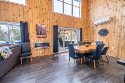 a dining room with a table and chairs and a clock at Nature Spa & Lake Access - Le Maikel in Beauceville-Est