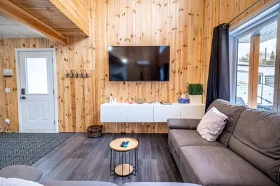 a living room with a couch and a tv on a wall at Nature Spa & Lake Access - Le Maikel in Beauceville-Est