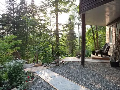 a porch of a house with a bench in the woods at Private Hummingbird Room - Modern & Cozy in Mansonville