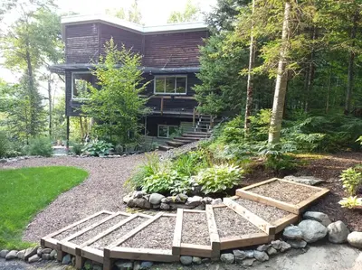 a house in the woods with two benches in the yard at Private Hummingbird Room - Modern & Cozy in Mansonville