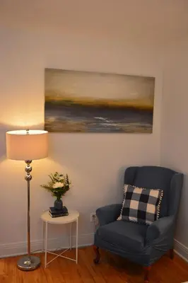a living room with a blue chair and a painting at Van Horne Sweet Celebration in Montréal