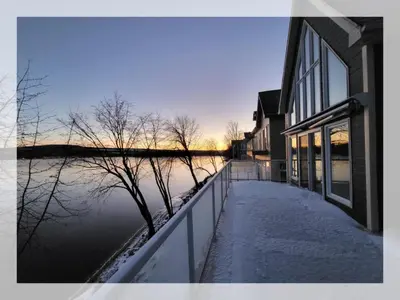 a house with a flooded street next to a body of water at Lakefront Spa - Chez Bernard L'Hermite in St-Ferdinand