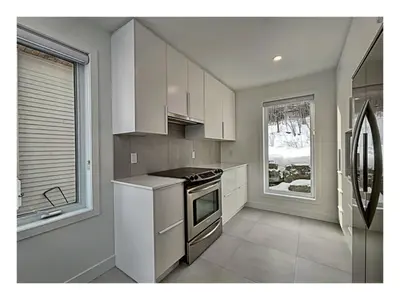 a kitchen with white cabinets and a stove top oven at Lakefront Spa - Chez Bernard L'Hermite in St-Ferdinand