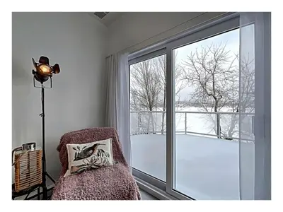 a room with a chair and a large window at Lakefront Spa - Chez Bernard L'Hermite in St-Ferdinand