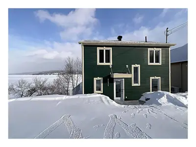 a green house with snow in front of it at Lakefront Spa - Chez Bernard L'Hermite in St-Ferdinand