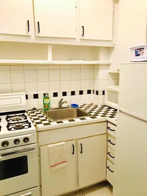 a white kitchen with a sink and a stove at Modern City Studio Living in the Golden Square Mile in Montréal
