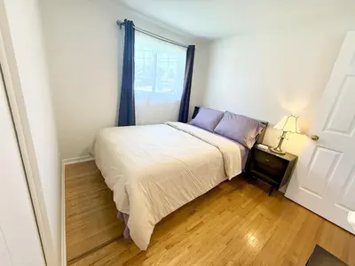 a small bedroom with a bed and a window at Warm Welcome Home in Longueuil