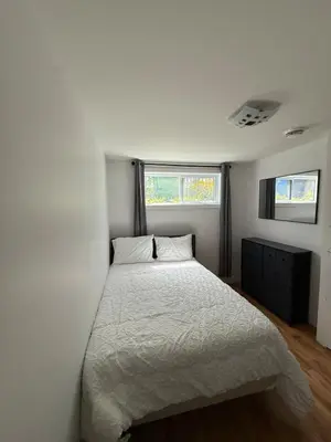 a white bedroom with a bed and two windows at Apartment 3 chambres near Montréal in Sainte-Catherine