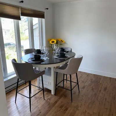 a dining room with a table with chairs and flowers at Apartment 3 chambres near Montréal in Sainte-Catherine